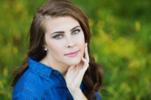 Girl Senior Photography in tall grass field with blue jean dress